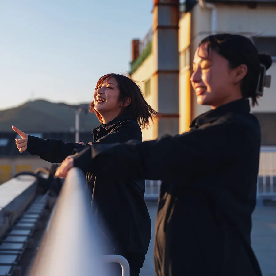 屋上で微笑んでいる女性社員2人
